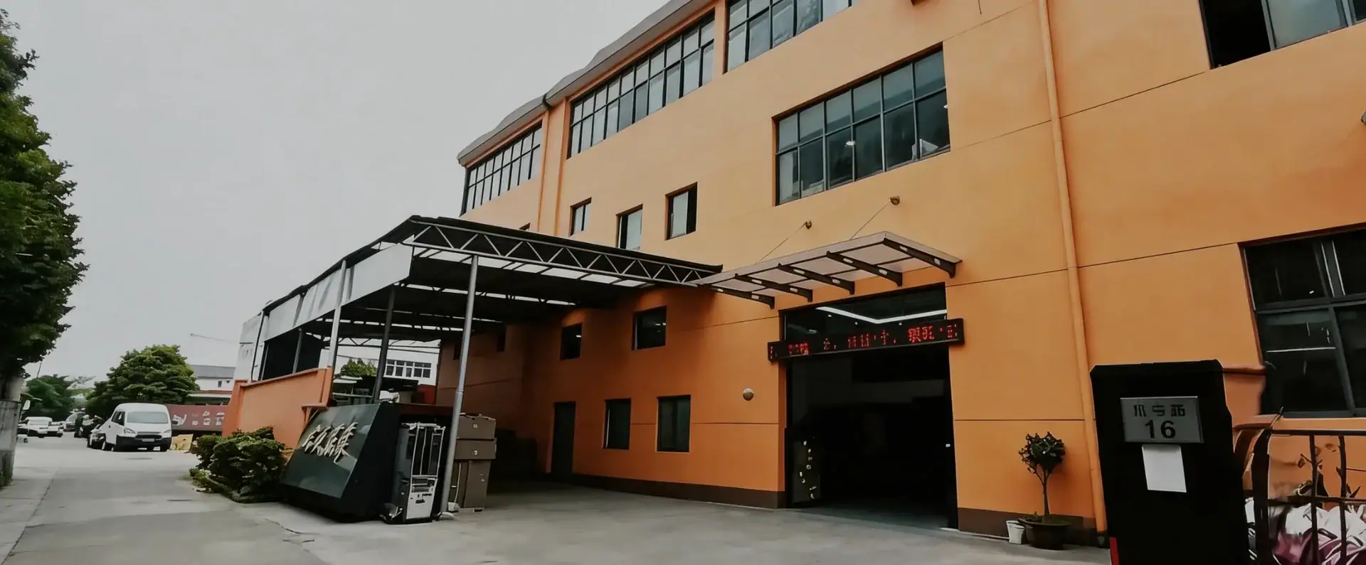 Contemporary commercial building with a covered entrance, large windows, and a parking area, located in an urban setting.