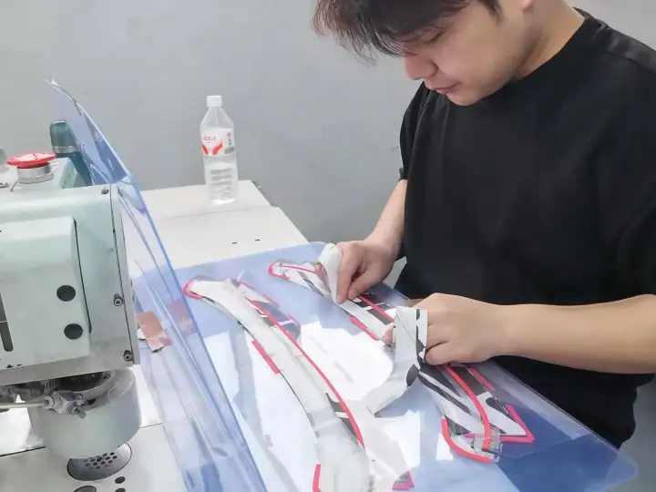 Young designer working on a fashion prototype with fabric and tools at a workspace.