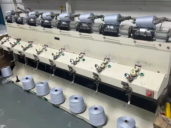 Industrial textile yarn spinning machine with multiple spindles producing yarn for fashion and apparel manufacturing.
