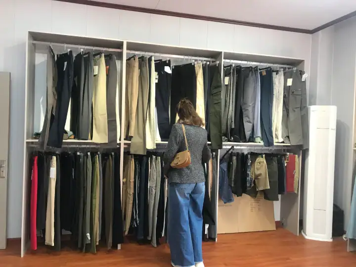 Customer browsing a wide selection of pants in a retail store, with various styles and colors on display racks.
