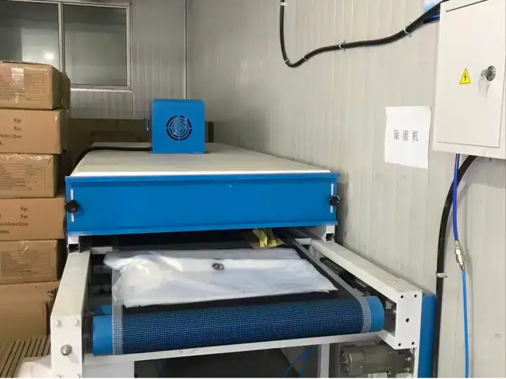 Industrial packaging machine with blue components in a factory setting, used for packaging fashion products efficiently.