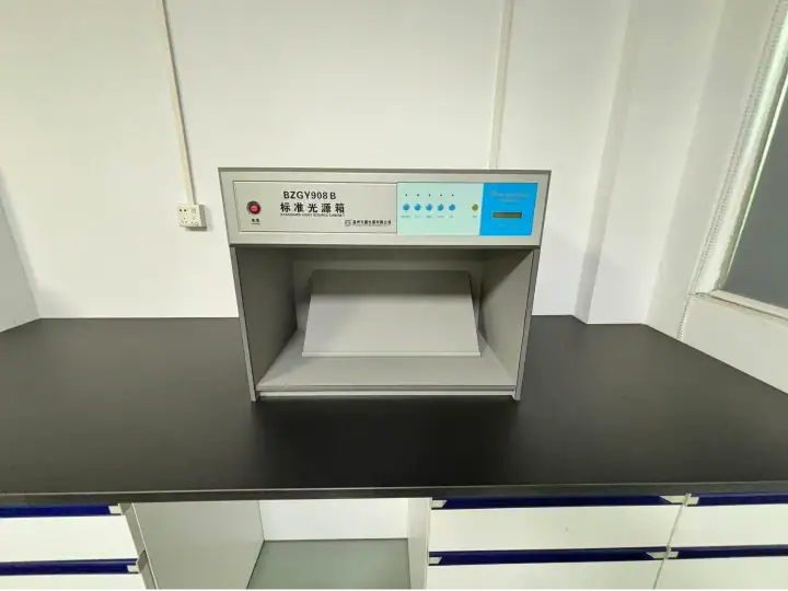 Laboratory testing device with digital control panel on a black countertop in a clean lab environment.