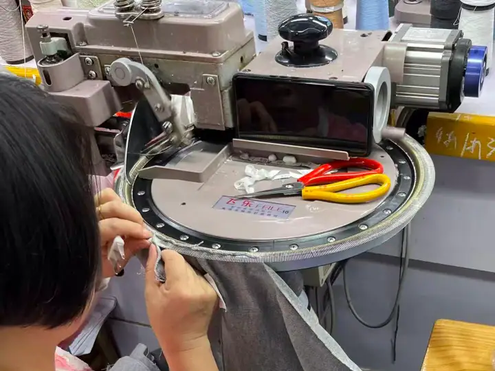 Close-up of an industrial sewing machine with tools and fabric, used for high-quality garment manufacturing.