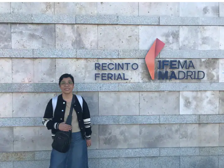 Person standing in front of the IFEMA Madrid sign at the exhibition center, wearing casual clothing and carrying a backpack.