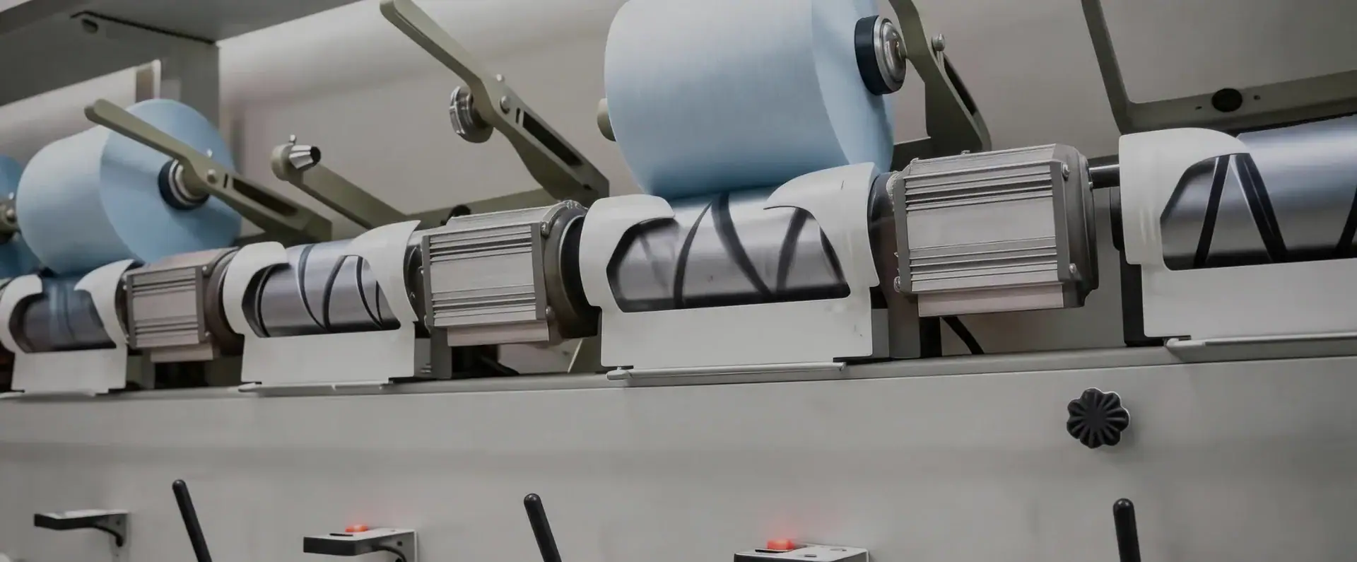 Close-up of an industrial fabric printing machine with rollers and printing heads, used in textile manufacturing.