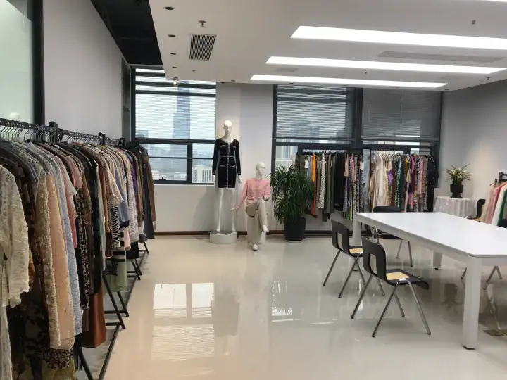 Modern fashion boutique interior featuring clothing racks with various garments, mannequins displaying outfits, and a bright, spacious environment with large windows.