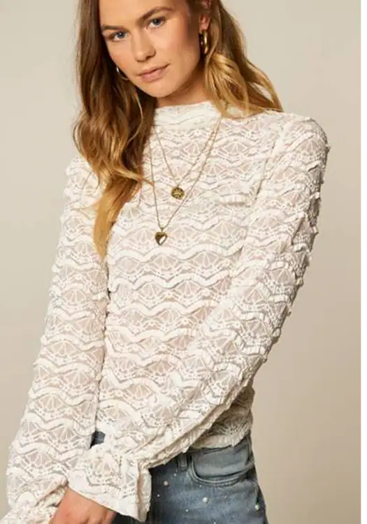 Fashionable white lace blouse with long sleeves, styled with layered gold necklaces, perfect for casual or semi-formal occasions.
