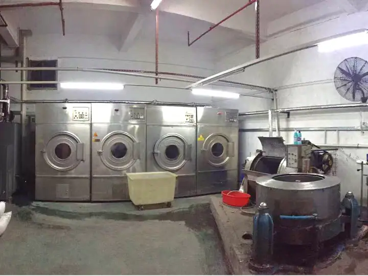 Industrial laundry room with multiple washing machines and industrial equipment for commercial laundry services.