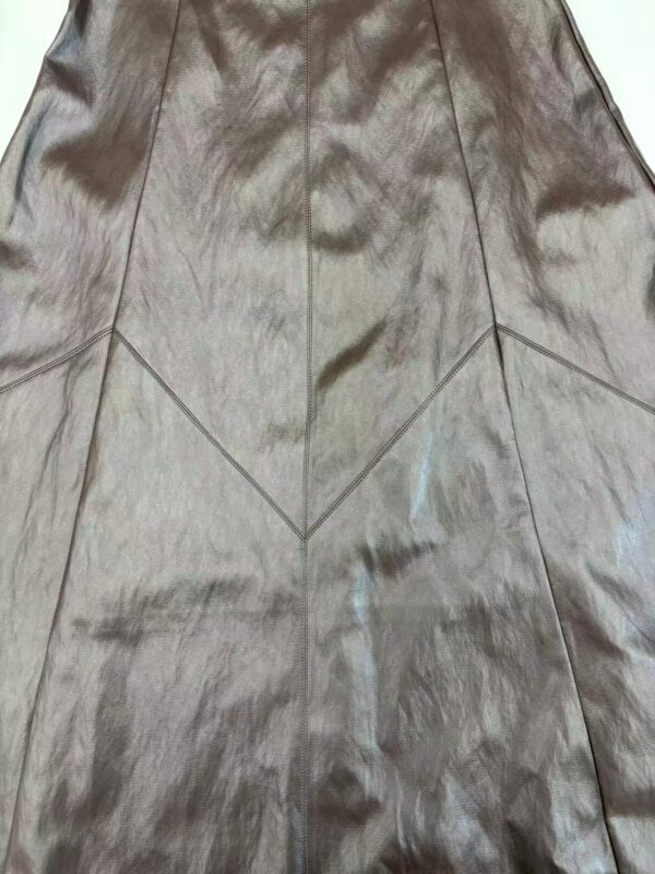 Close-up of a shiny metallic leather skirt with geometric paneling, perfect for stylish and modern fashion looks.