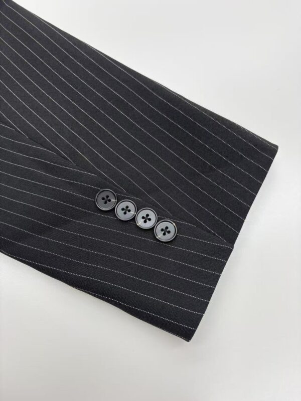 Close-up of a black pinstripe suit sleeve with four buttons, showcasing professional men's fashion and tailored clothing.