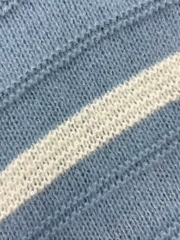 Detailed close-up of blue knitted fabric with a white stripe, showcasing the texture and weave of the material, ideal for fashion and textile SEO.