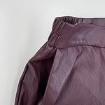 Close-up of burgundy leather pants with elastic waistband, showcasing high-quality material and fashionable design for women.