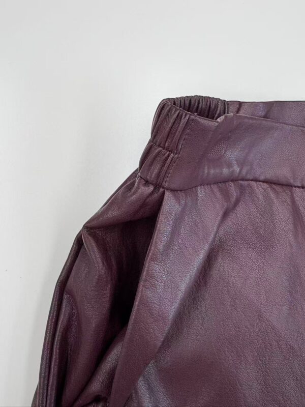 Close-up of burgundy leather pants with elastic waistband, showcasing high-quality material and fashionable design for women.
