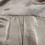 Close-up of beige dress fabric with pleats and stitching, showcasing high-quality material and craftsmanship.