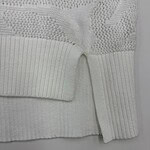 Close-up of a white knit sweater featuring intricate lace and ribbed details, perfect for stylish winter wear.