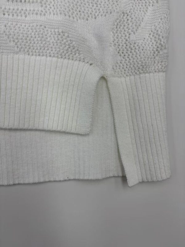Close-up of a white knit sweater featuring intricate lace and ribbed details, perfect for stylish winter wear.
