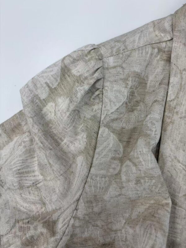 Close-up of a beige linen blouse with puffed sleeves and subtle print, perfect for casual or formal wear.