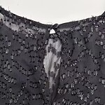 Close-up of a black dress with intricate beadwork and sequins, showcasing fine craftsmanship and luxurious fabric suitable for formal occasions.