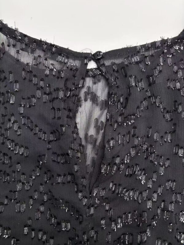 Close-up of a black dress with intricate beadwork and sequins, showcasing fine craftsmanship and luxurious fabric suitable for formal occasions.