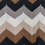 Close-up of chevron knit fabric in shades of brown, black, gray, and white, showcasing textured pattern and intricate stitching.