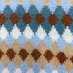 Close-up of a vibrant argyle pattern wool sweater featuring shades of blue, brown, beige, and white, showcasing a classic and cozy design.