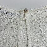 Close-up of intricate white lace fabric with floral and geometric patterns, showcasing fine craftsmanship and delicate texture.