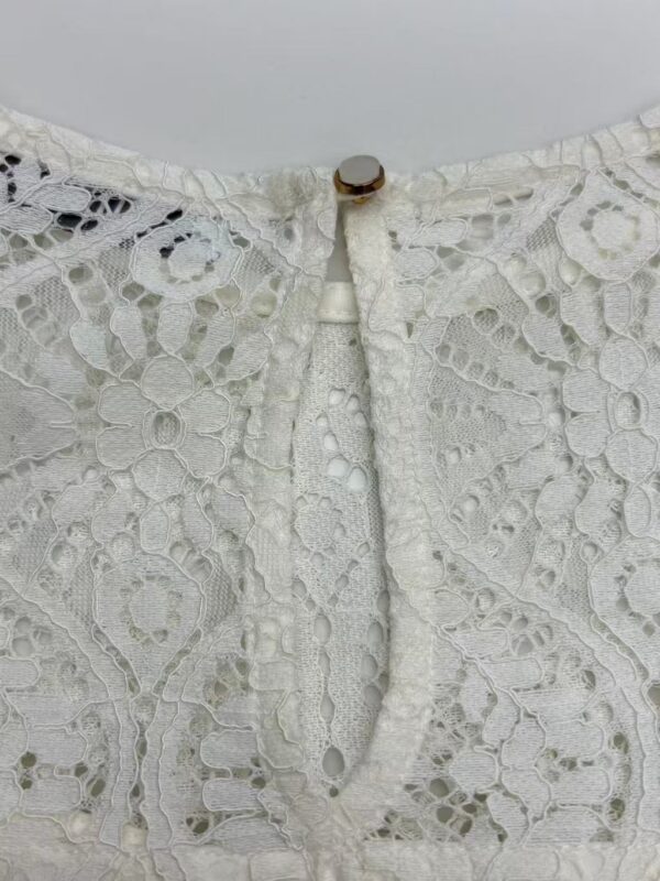 Close-up of intricate white lace fabric with floral and geometric patterns, showcasing fine craftsmanship and delicate texture.