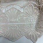 Close-up of intricate white lace fabric with floral and geometric patterns, ideal for fashion and wedding dress embellishments.