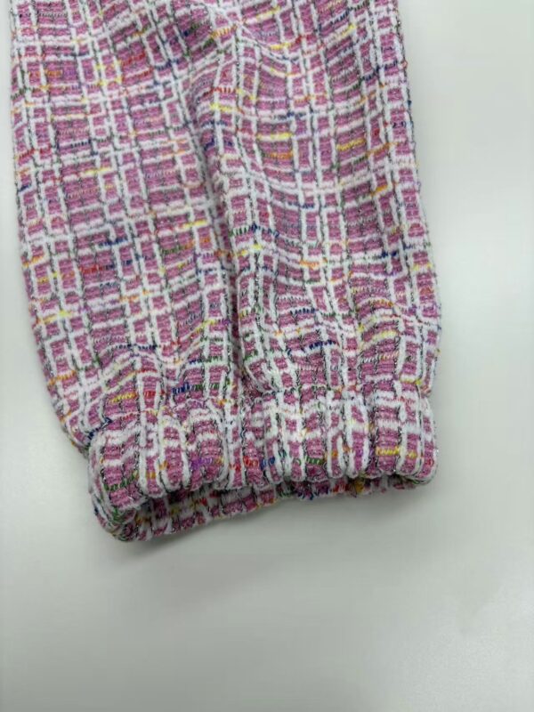 Close-up of vibrant pink, yellow, and white tweed fabric with a textured pattern, suitable for stylish clothing and accessories.