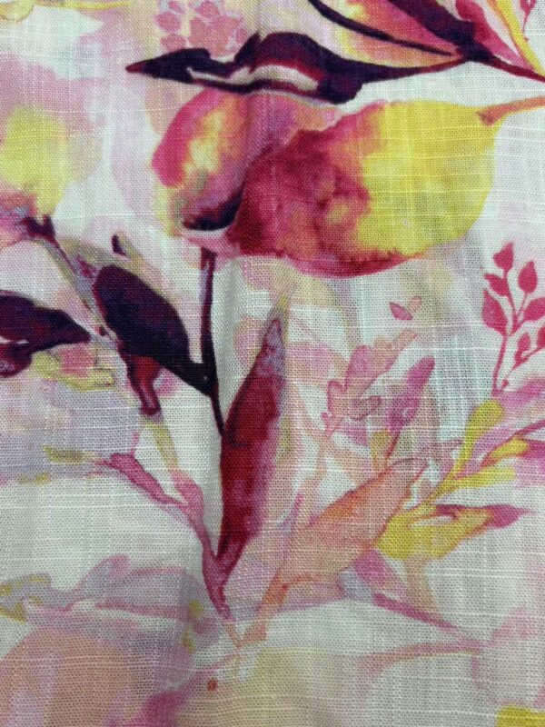 Close-up of a floral fabric pattern featuring pink, yellow, and purple watercolor-style flowers and leaves, ideal for fashion and home decor.