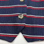 Close-up of navy blue blazer with red and white horizontal stripes and beige buttons, showcasing detailed fabric texture and design.