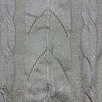 Close-up of silver beaded fabric with intricate leaf and vine patterns, perfect for luxury fashion and evening wear.