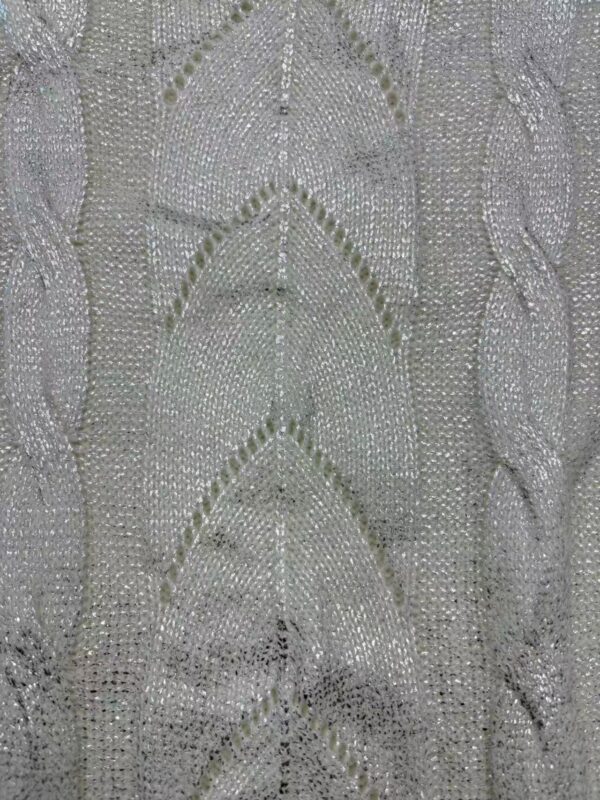 Close-up of silver beaded fabric with intricate leaf and vine patterns, perfect for luxury fashion and evening wear.