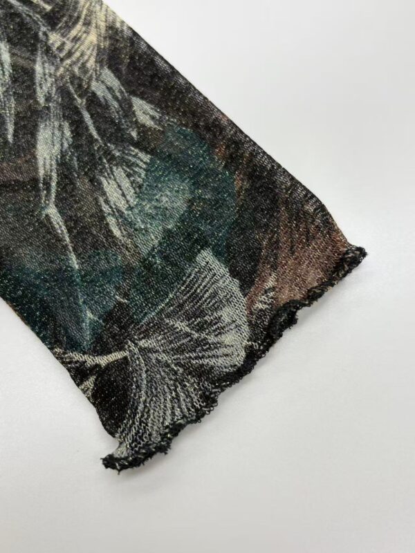 Close-up of a fabric with a detailed floral pattern in dark green, black, and beige tones, showcasing fine textile craftsmanship.