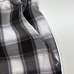 Close-up of plaid fabric with black, white, and gray pattern and a white zipper on the side.