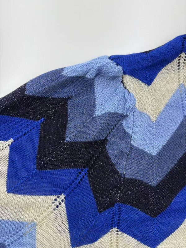 Close-up of a vibrant, geometric knitted textile with shades of blue, black, and beige, showcasing intricate patterns and craftsmanship.