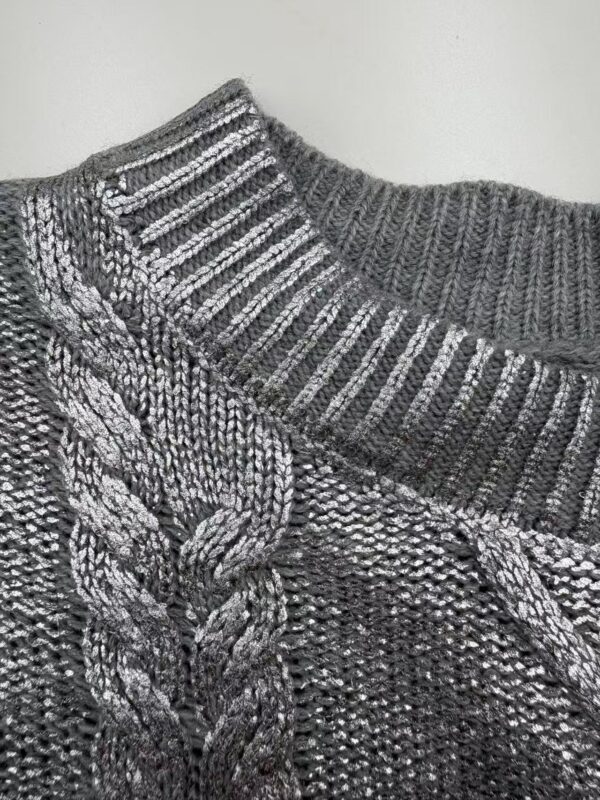 Close-up of a gray cable knit sweater with ribbed collar, showcasing detailed knitting pattern and texture.