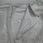 Close-up of a white lace dress with a zipper, showcasing intricate lace patterns and delicate fabric details for stylish women's fashion.