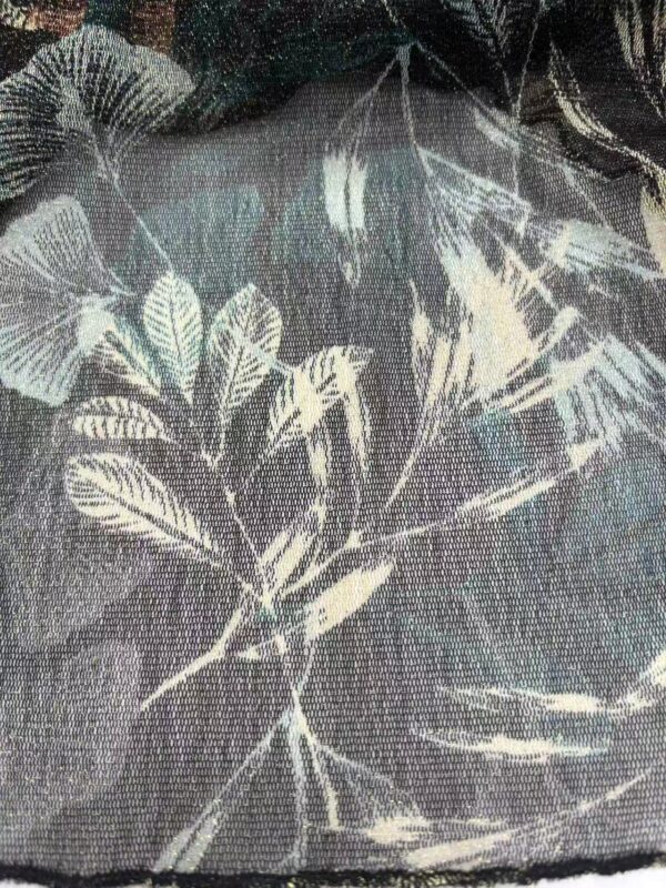 Close-up of fabric with botanical print featuring leaves and branches in muted tones, ideal for fashion and home decor.