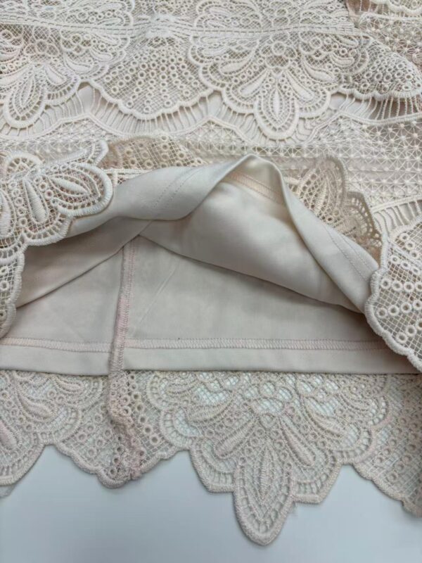 Close-up of intricate lace fabric with floral and geometric patterns, perfect for wedding dresses and elegant garments.
