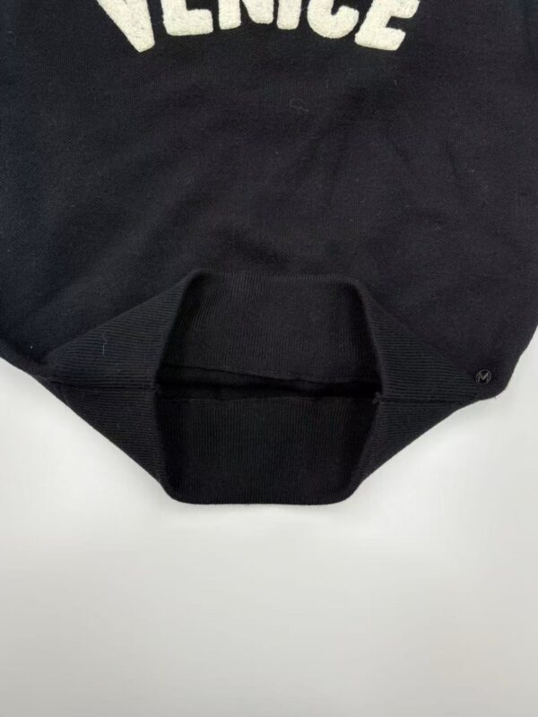Close-up of a black Versace T-shirt featuring the brand's logo in white letters on the front.