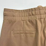 Close-up of beige casual men's pants with elastic waistband and back pocket, suitable for everyday wear and comfortable fashion.