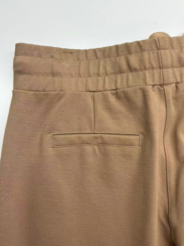 Close-up of beige casual men's pants with elastic waistband and back pocket, suitable for everyday wear and comfortable fashion.