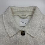 Close-up of a white cotton coat with a textured fabric and a single button, perfect for stylish winter wear.
