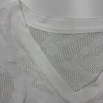 Close-up of a white knit sweater with a V-neck and textured pattern, perfect for casual or stylish wear.