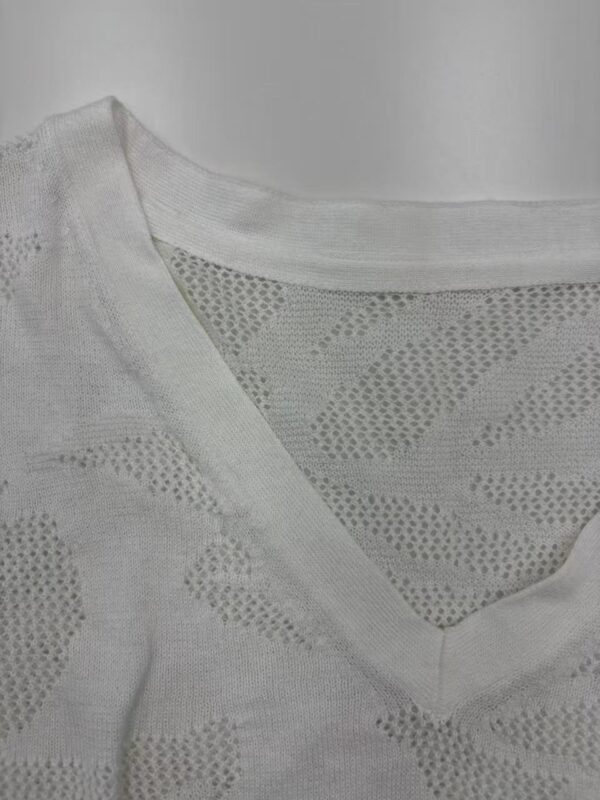 Close-up of a white knit sweater with a V-neck and textured pattern, perfect for casual or stylish wear.
