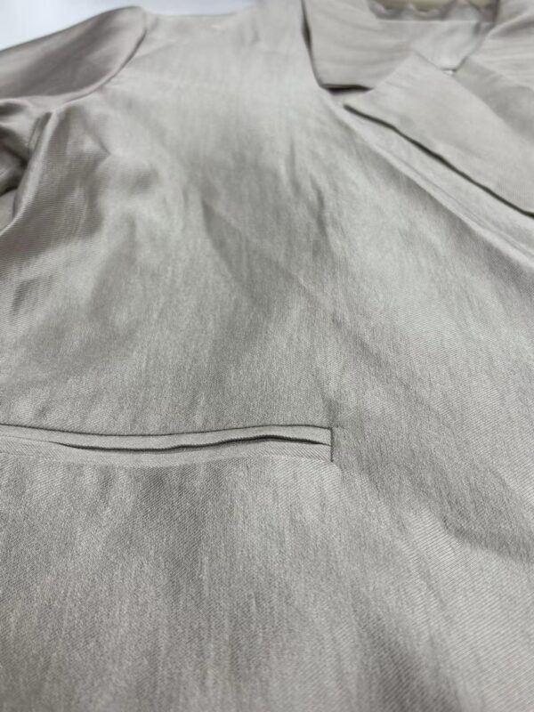 Close-up of a light gray men's dress shirt with a pocket and subtle fabric texture, suitable for formal or business wear.