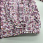 Close-up of a vibrant pink, yellow, and purple tweed fabric with intricate woven pattern, suitable for fashion and textile design.