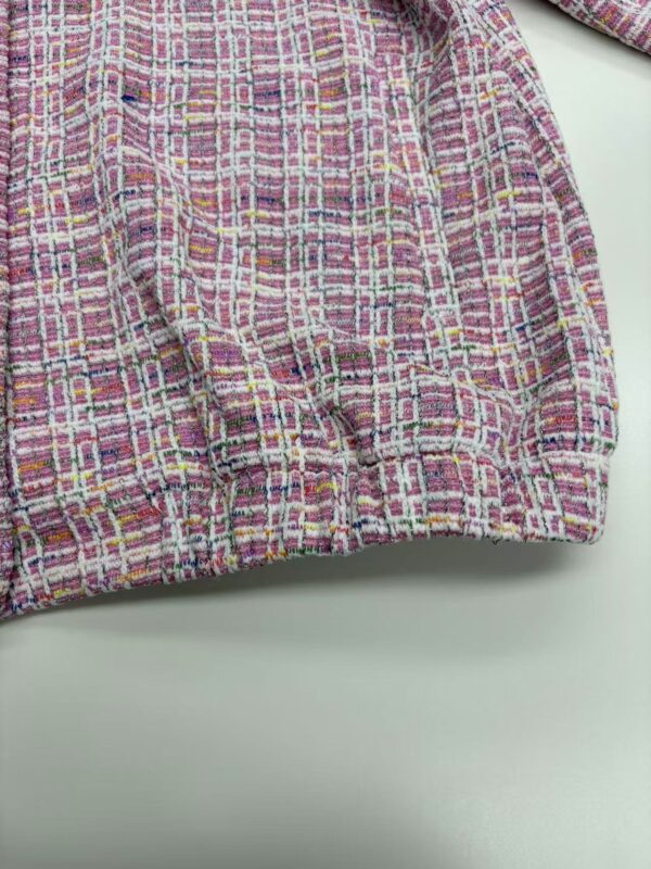 Close-up of a vibrant pink, yellow, and purple tweed fabric with intricate woven pattern, suitable for fashion and textile design.