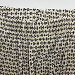 Close-up of fabric featuring a black and white geometric pattern with small diamond and square shapes, gathered at the top.